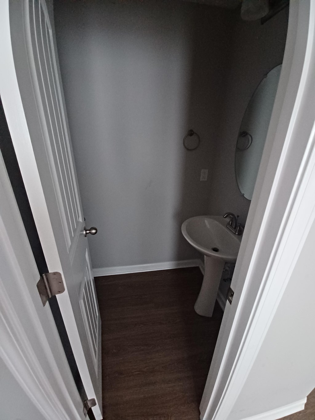A white door is open to a small bathroom with a toilet and sink.