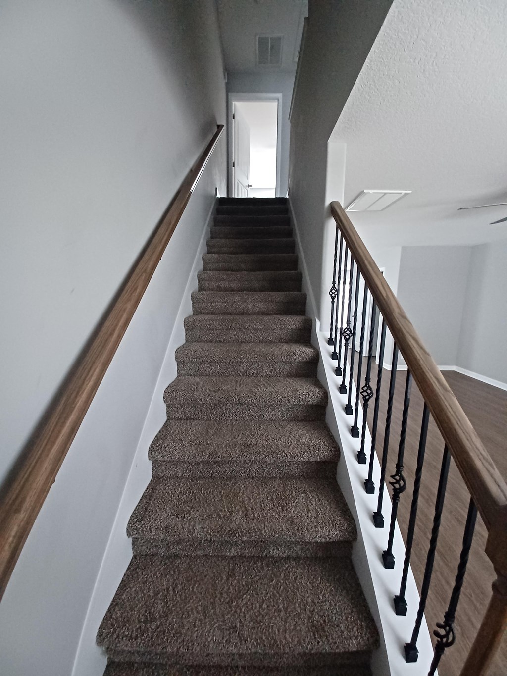 A staircase with a carpeted runner and wooden handrails.