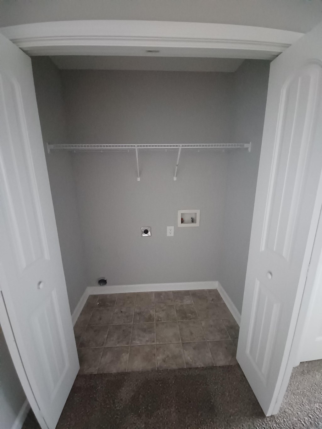 A white closet with a shelf and a carpeted floor.