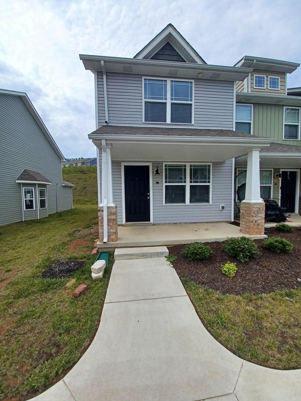 A house with a grey front and a black car in the driveway.