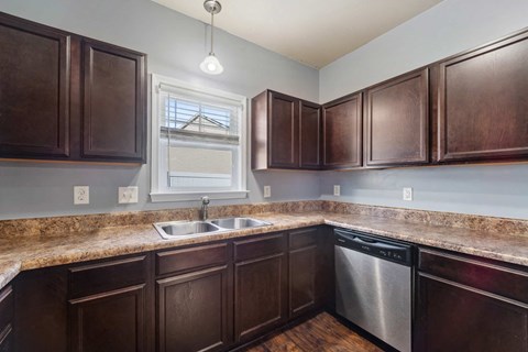A kitchen with brown cabinets and a granite countertop.