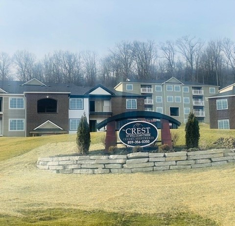 a view of the crest condominiums in front of a field and a sign