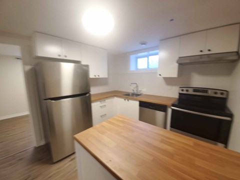 A kitchen with a wooden counter top and stainless steel appliances.