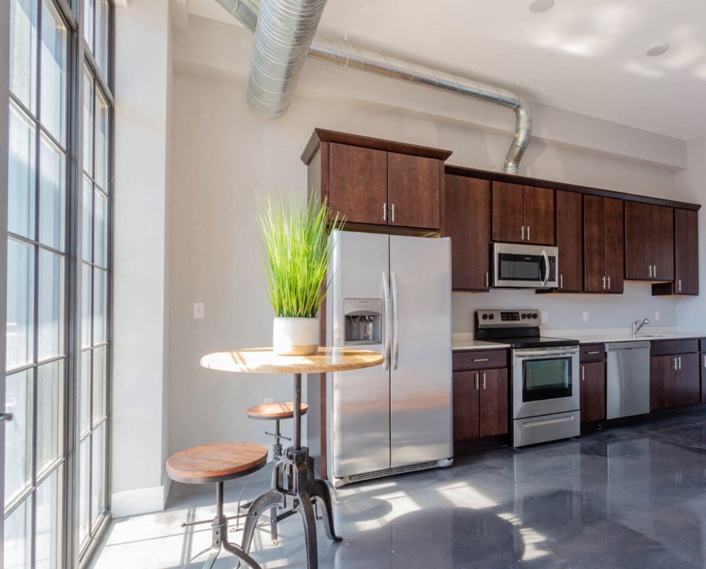 a kitchen with stainless steel appliances and a round table with two stools