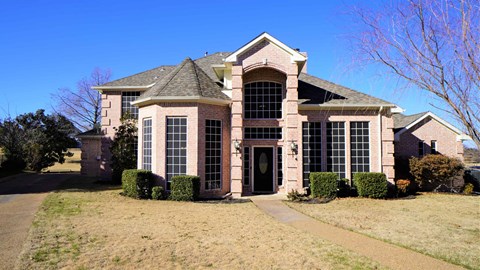 a large brick house with a sidewalk in front of it