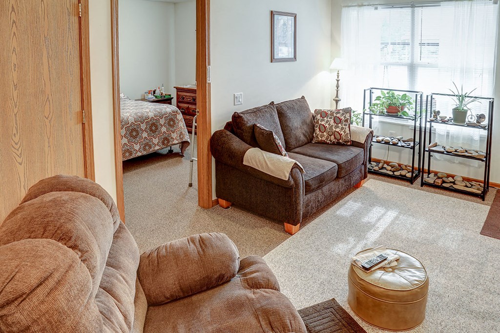 a living room with a couch and chair and a bedroom with a bed