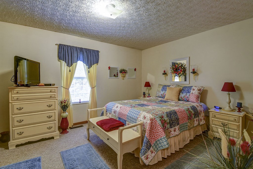 a bedroom with a bed and a dresser and a tv