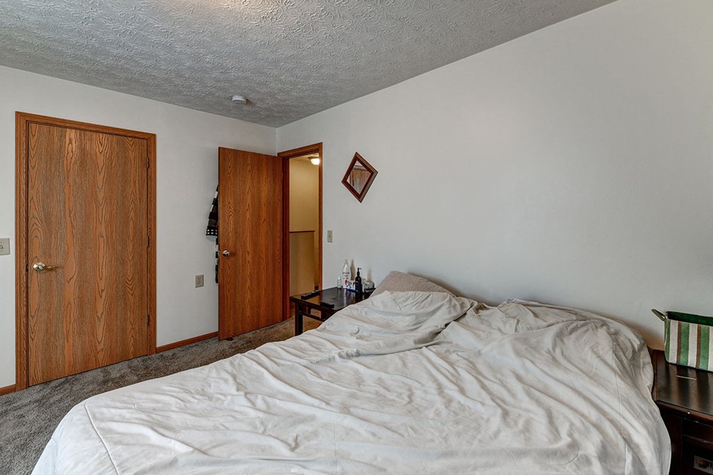 a bedroom with an unmade bed and a door to a bathroom