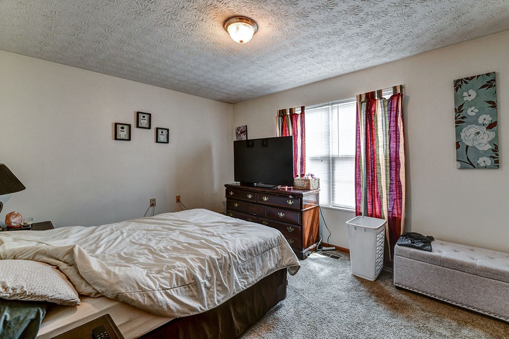 a bedroom with a bed and a dresser and a tv