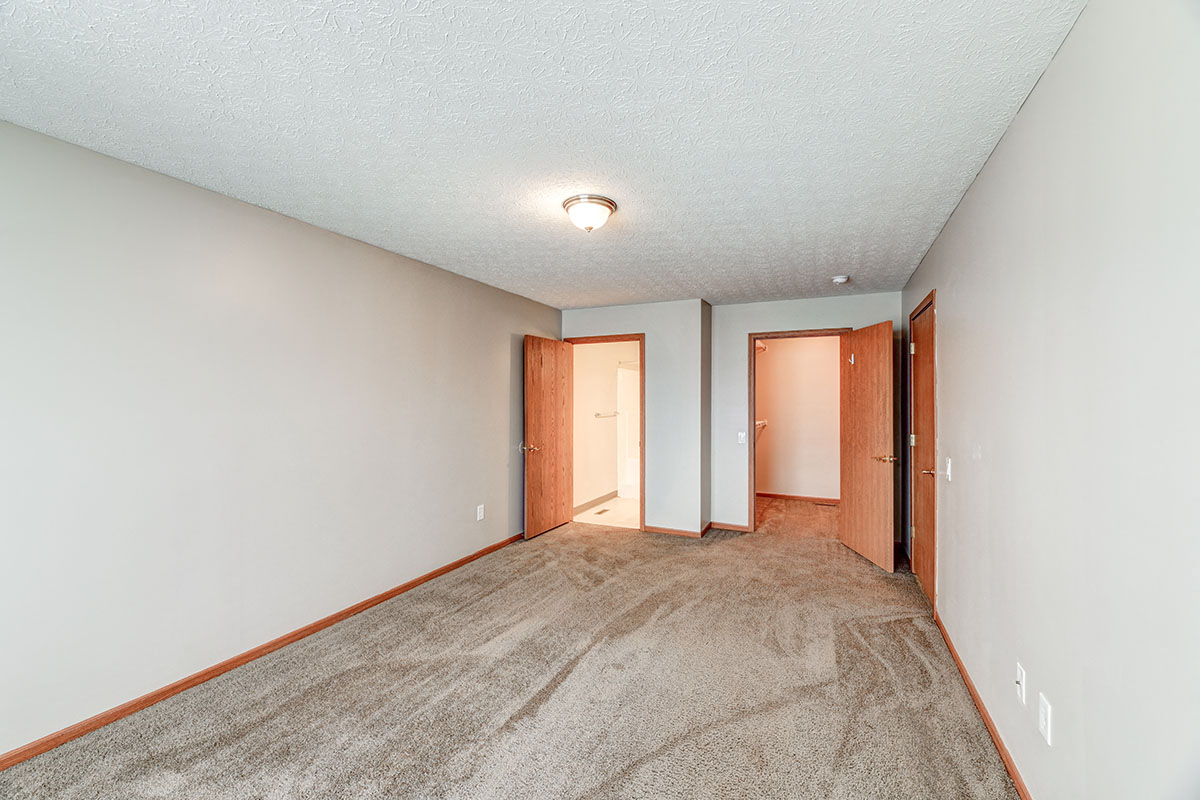 a spacious living room with carpet and a door to a hallway