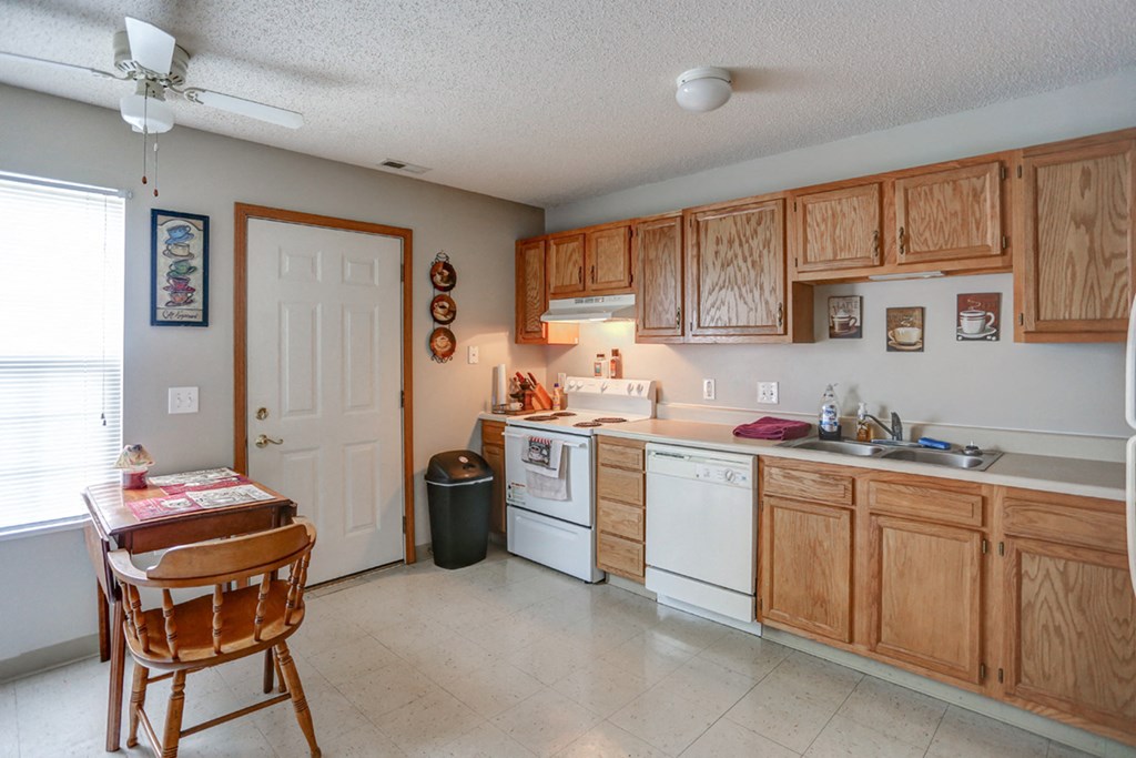a kitchen with white appliances and wooden cabinets and a table