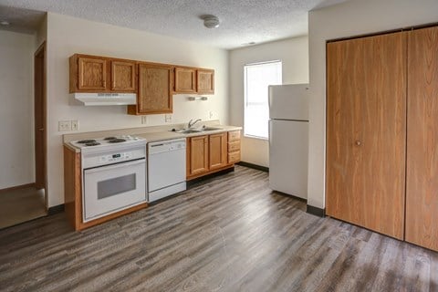 an empty kitchen with wood flooring and white appliances