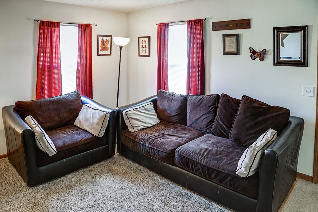 a living room with leather couches and red curtains