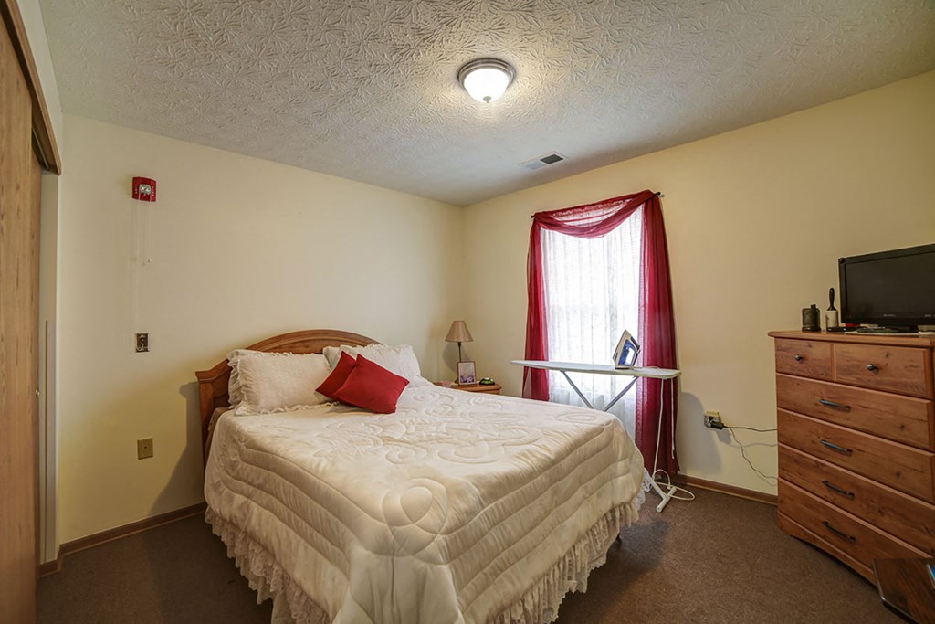 a bedroom with a bed and a dresser and a window