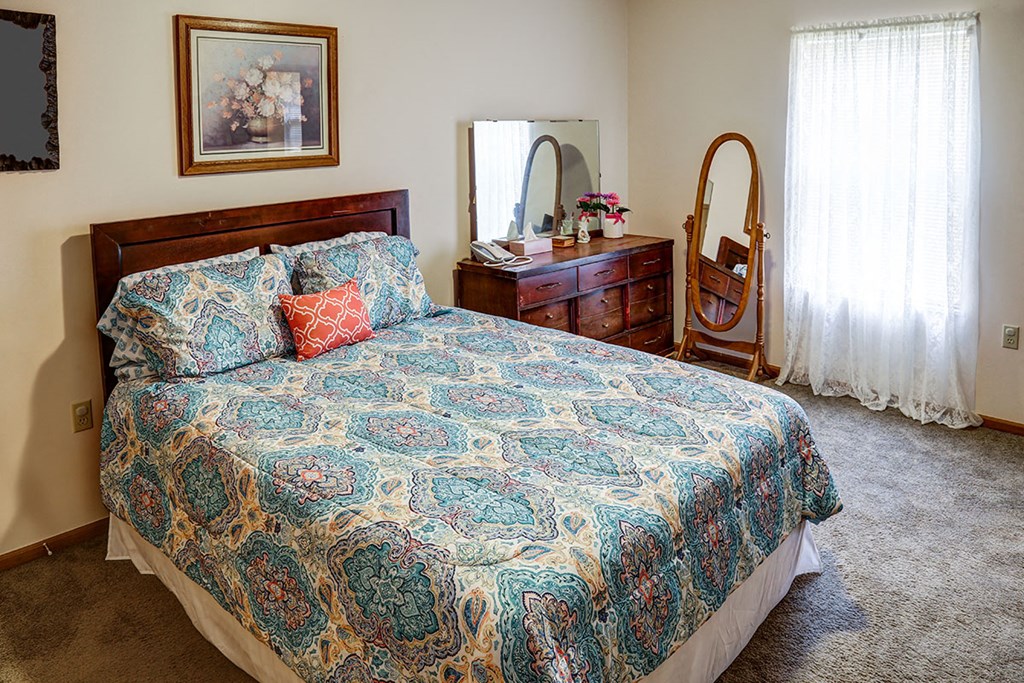 a bedroom with a bed and a dresser with a mirror