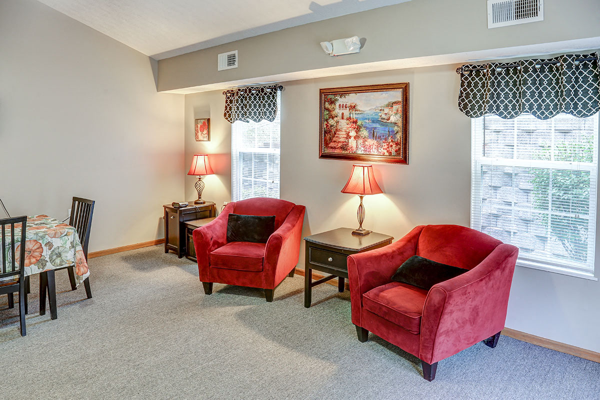 a living room with two red chairs and a table