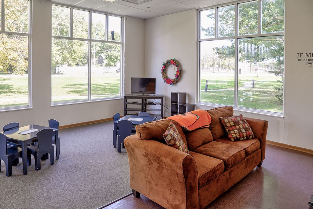 a living room with a couch and chairs and large windows