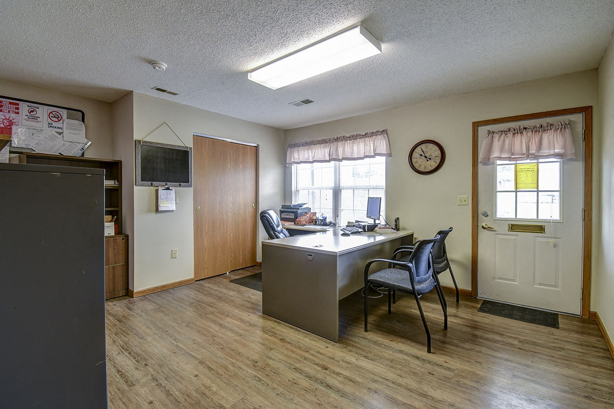 an office space with a desk and chairs and a window