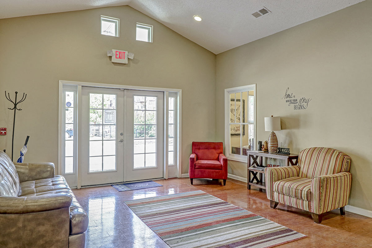 a living room with doors and chairs and a rug
