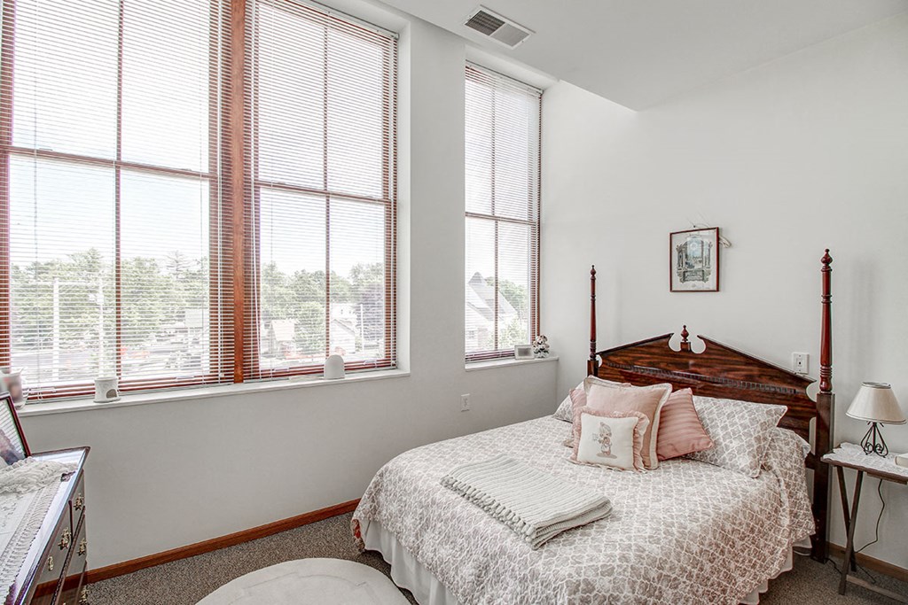 a bedroom with a bed and three windows