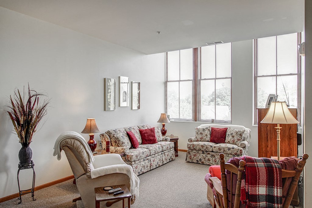 a living room with couches and chairs and windows