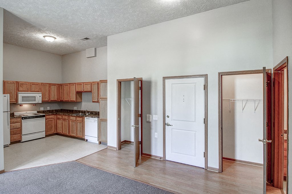 an empty kitchen and living room with wooden cabinets