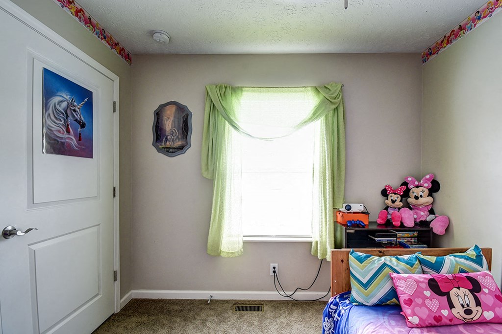a bedroom with a bed and a window with green curtains