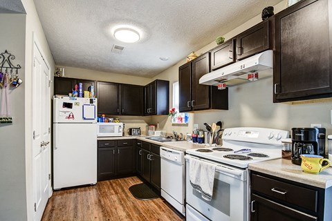 a kitchen with white appliances and dark cabinets