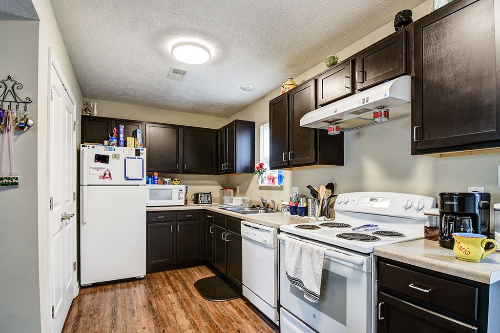 a kitchen with white appliances and dark cabinets