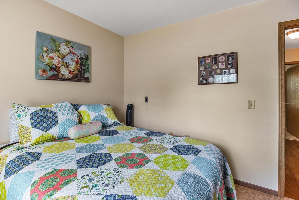 a bedroom with a bed and a colorful quilt