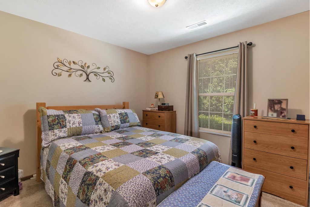 a bedroom with a bed and a dresser and a window