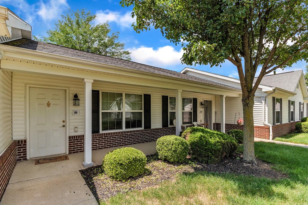 the front of a house with a porch and a tree
