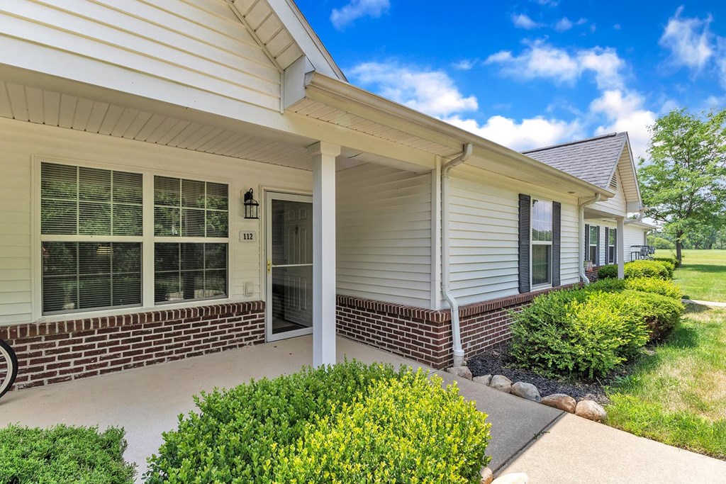 the front entrance of a house with a driveway and a porch