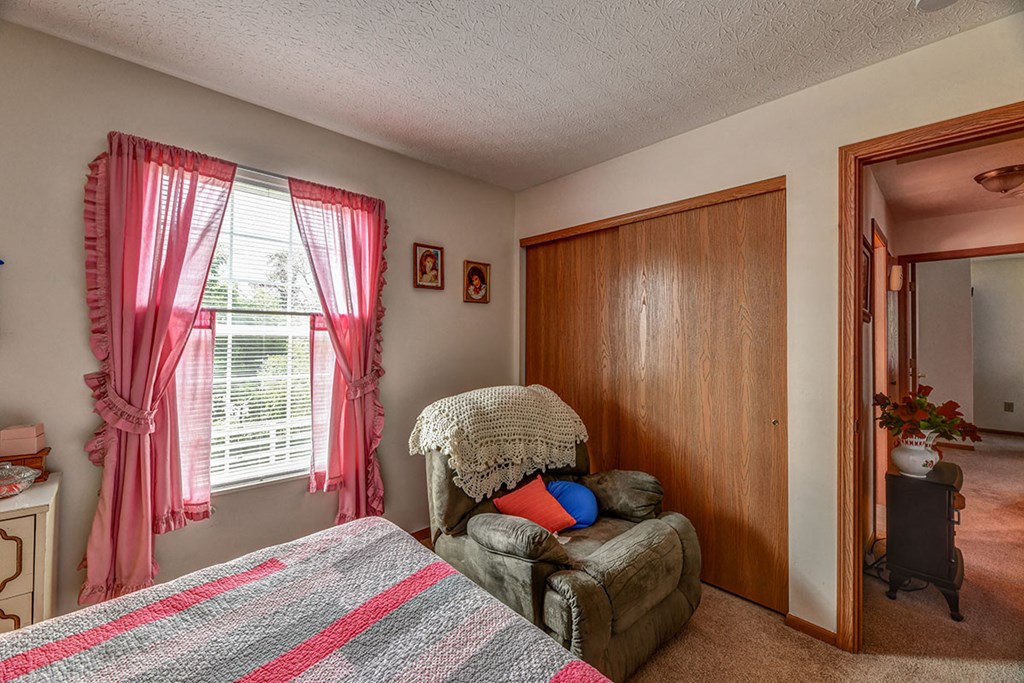 a bedroom with a chair and a bed and a closet