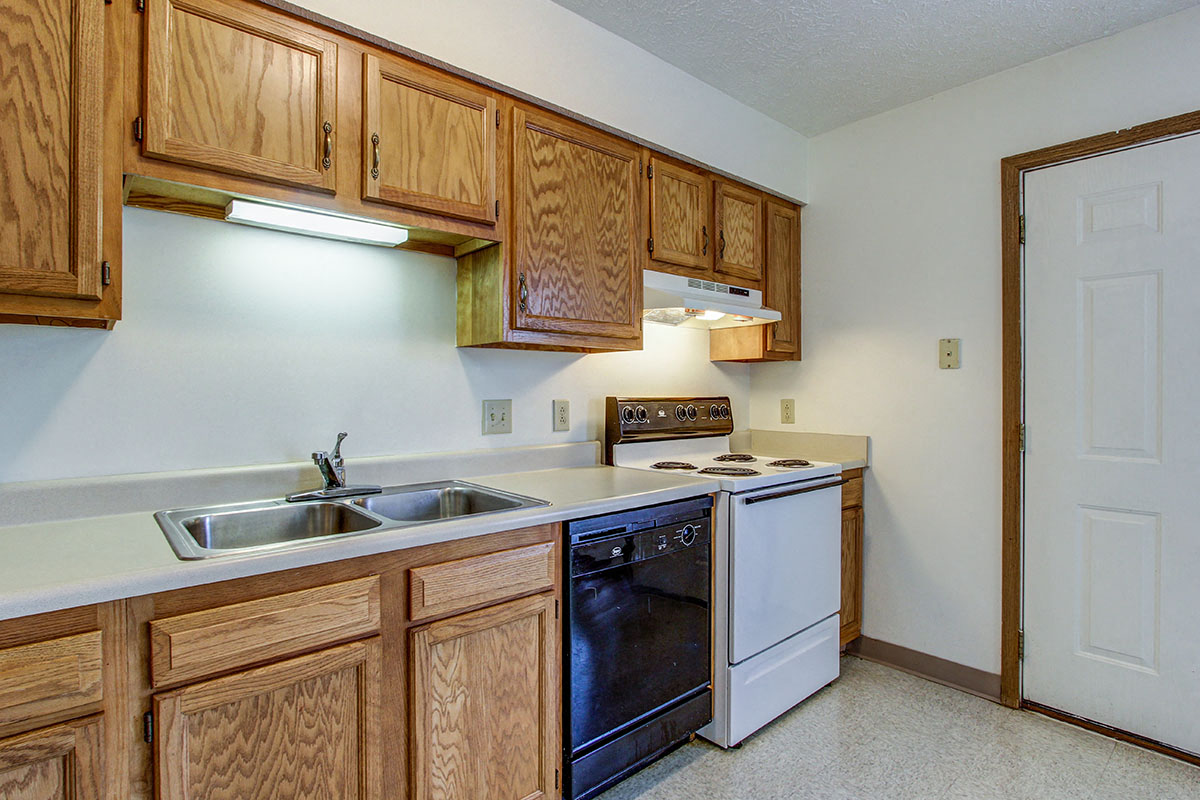 a kitchen with wooden cabinets and a white stove and sink