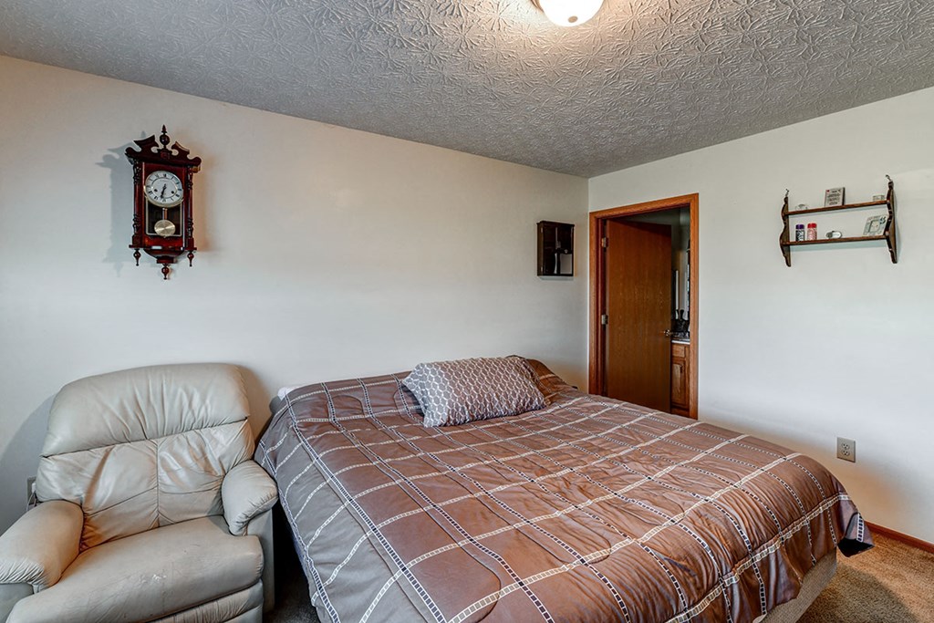a bedroom with a bed and a leather chair