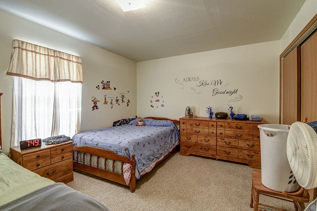a bedroom with a bed and dresser and a fan