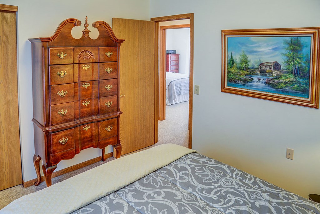 a bedroom with a dresser and a door to a bathroom