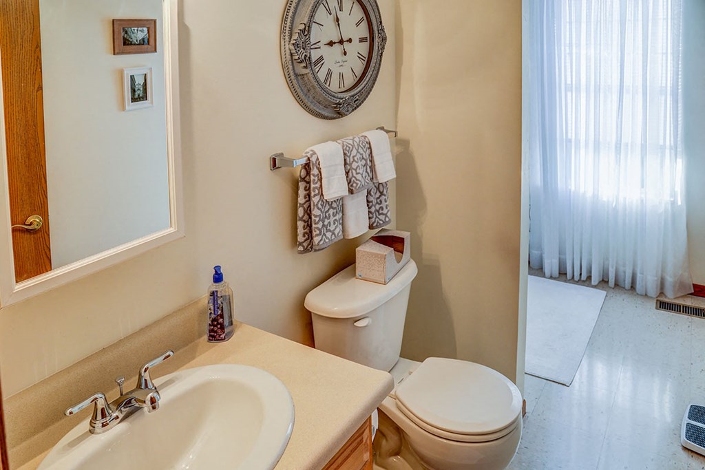 a bathroom with a clock on the wall above the toilet