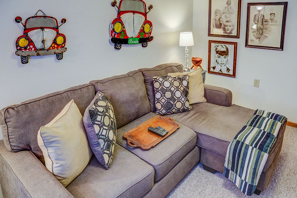 a couch with pillows in a living room with pictures on the wall