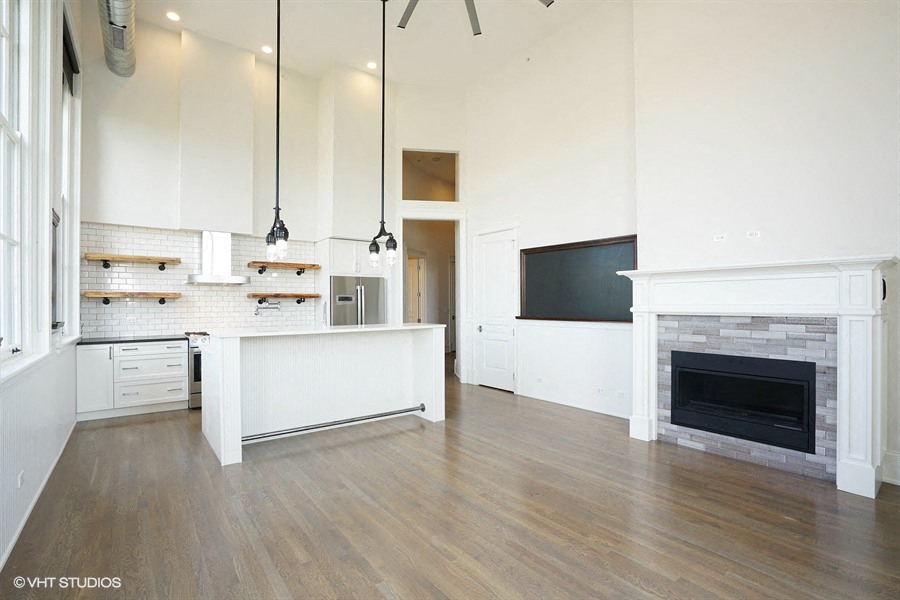 an open kitchen and living room with white cabinets and a fireplace