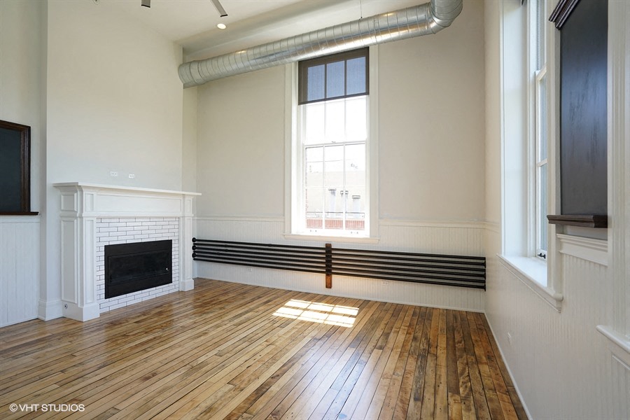 an empty living room with a fireplace and wooden floors