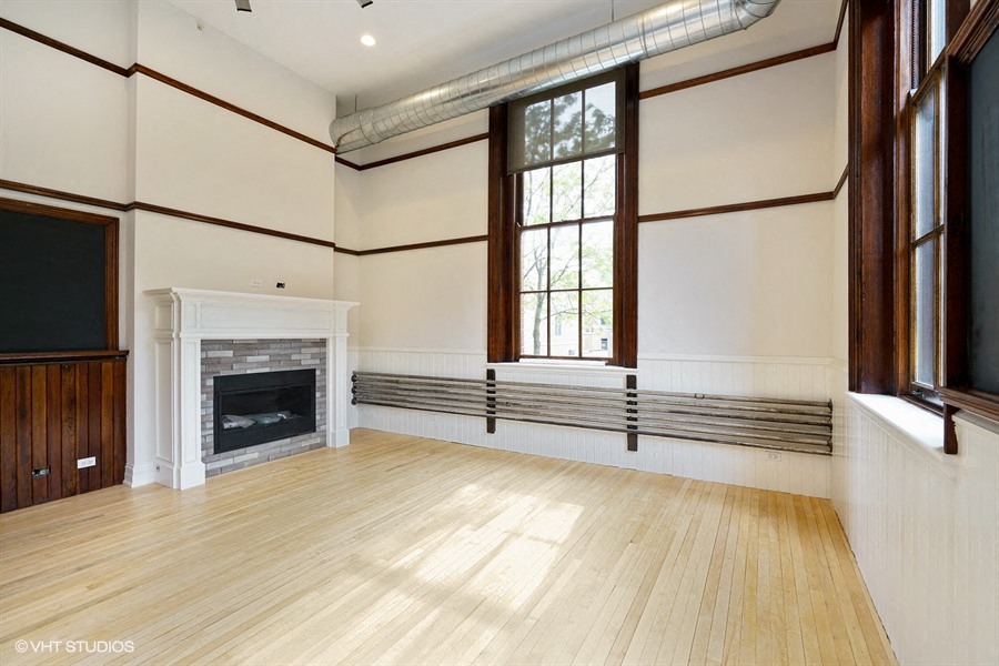 the living room of a house with a fireplace and wooden floors