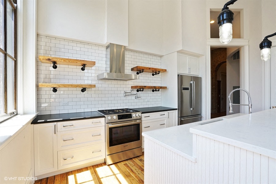 a kitchen with white cabinets and black counter tops