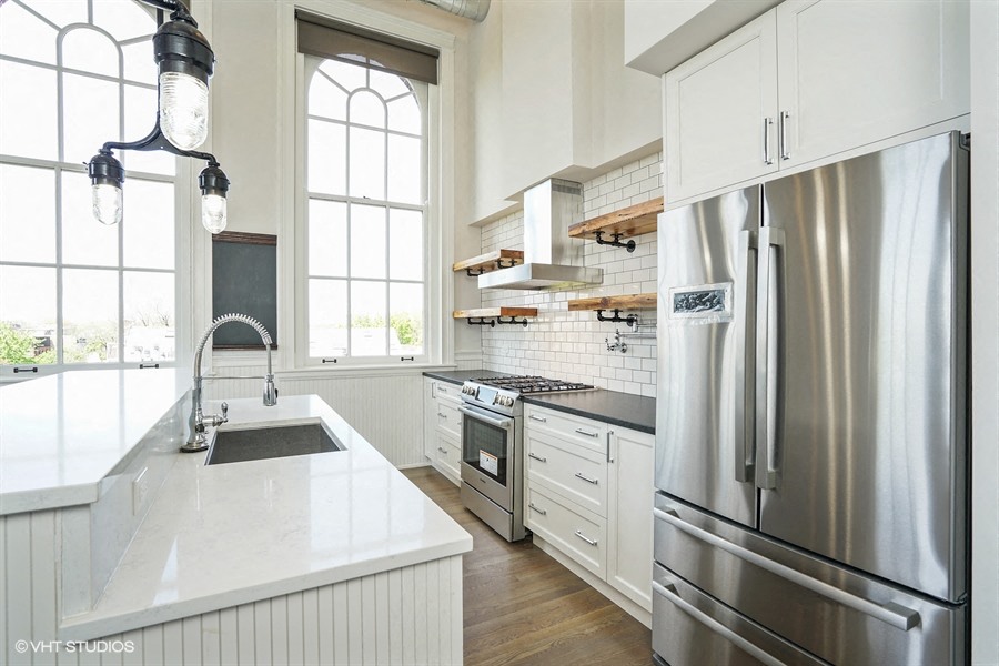 a white kitchen with stainless steel appliances and a large window
