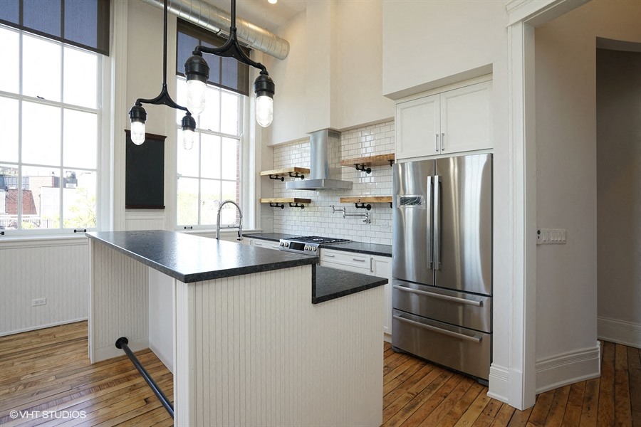 a kitchen with a large island and a stainless steel refrigerator