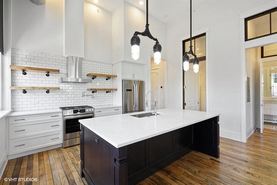 a large white kitchen with a large island in the middle