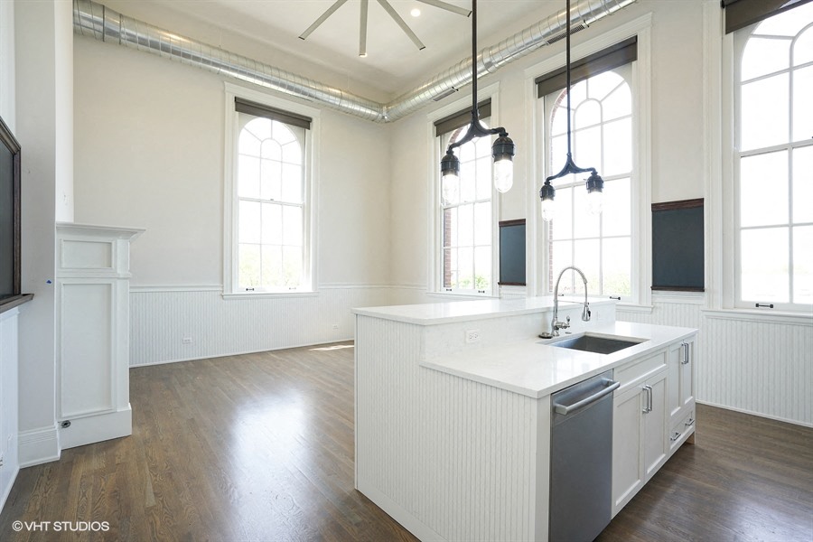 an open kitchen with white cabinets and a large white counter top