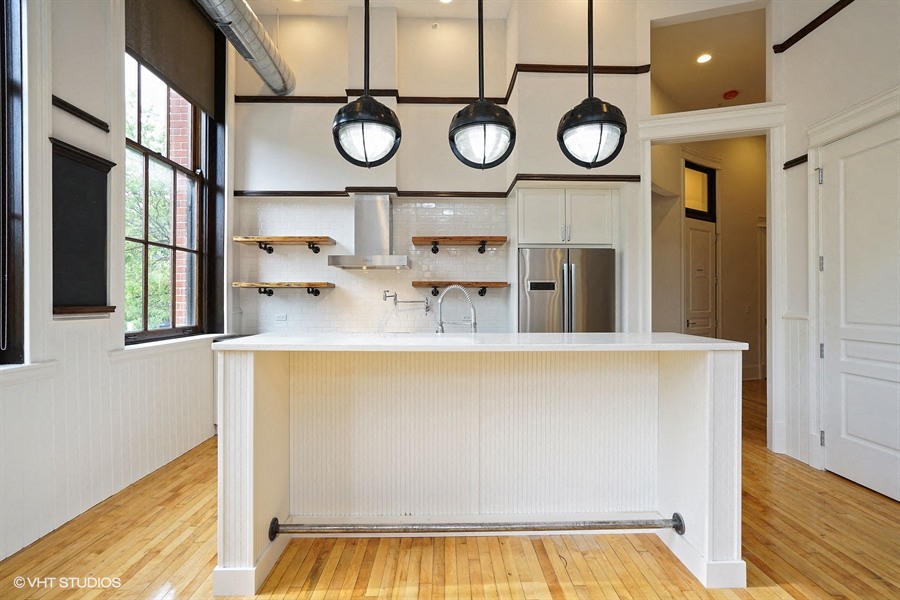 a large white kitchen with a large island in the middle