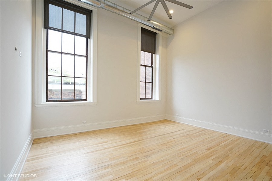 an empty room with two windows and a wooden floor